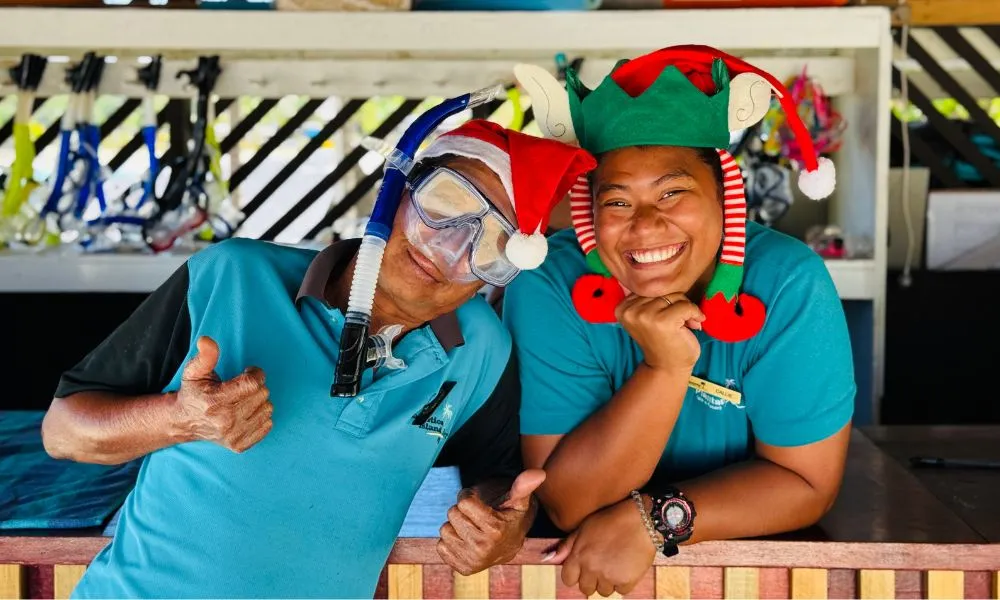 Two Plantation Island Resort team members smiling wearing festive hats