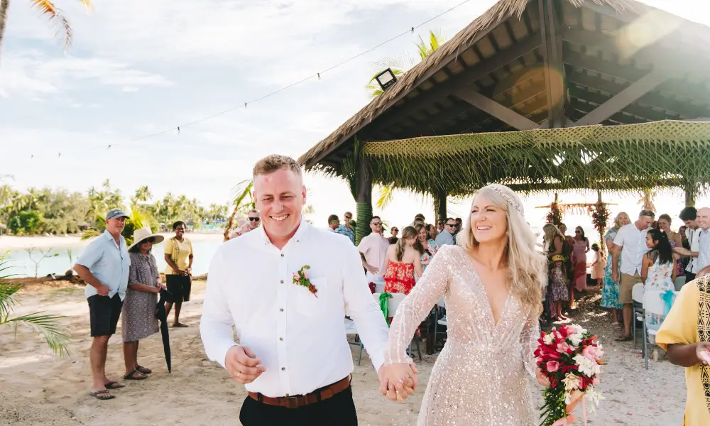 A married couple leaving the ceremony among family and friends.