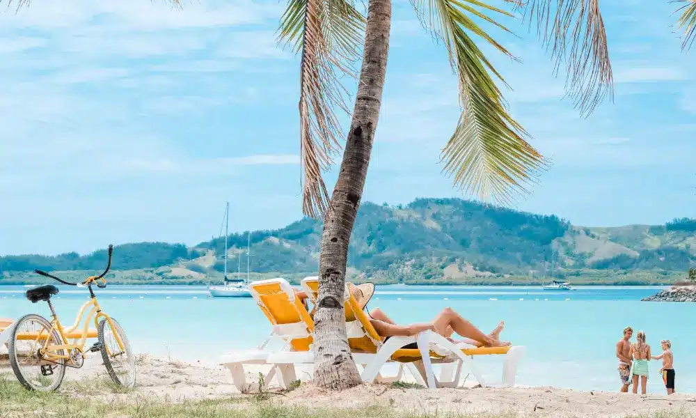 Parents relax on the beach while kids play in the water at Plantation Island Resort.