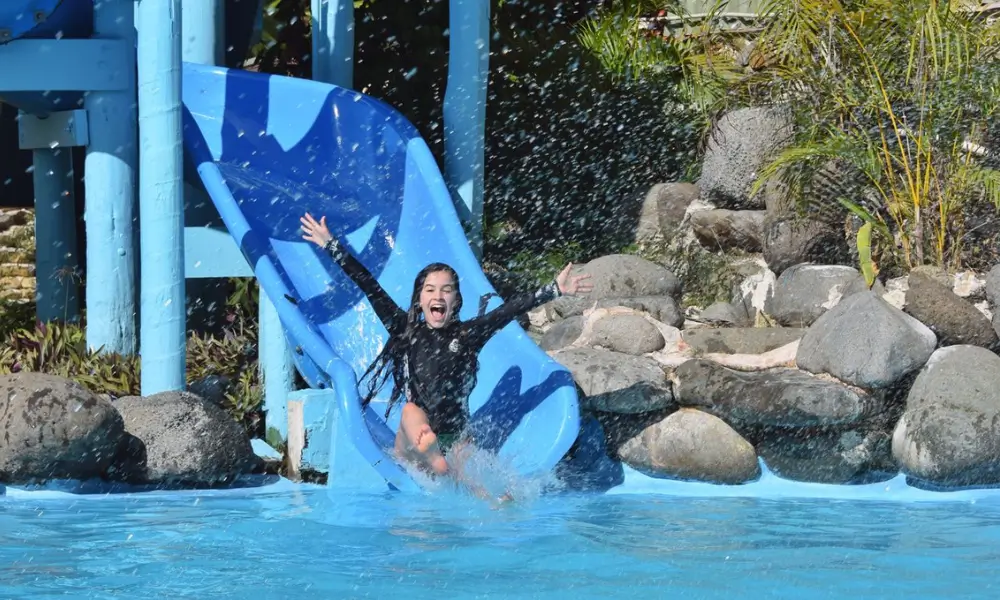 A young girl sliding down a blue waterslide