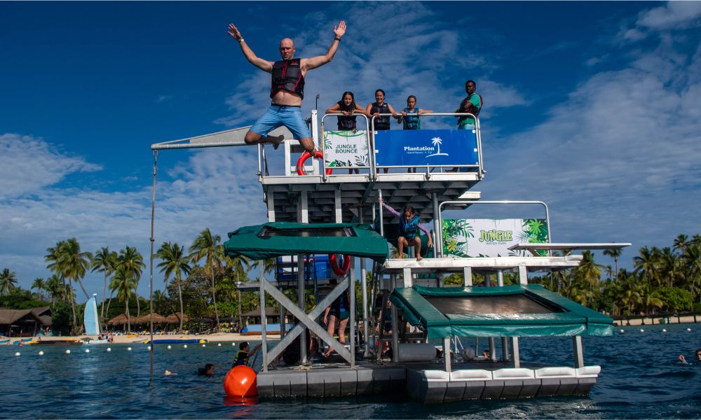Family enjoying the Jungle Water Park at Plantation Island Resort, watching a man jump from the platform into the water
