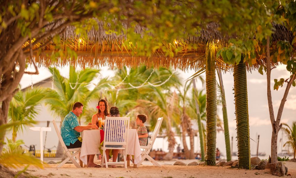 Family dining together at a table on the sand at Plantation Island Resort