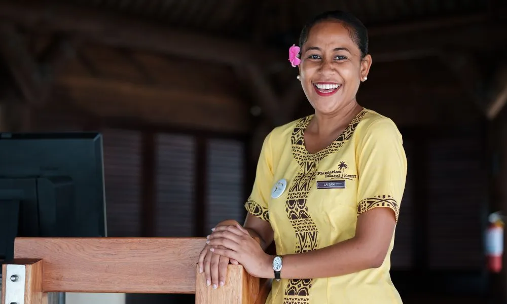 Photograph of Plantation female staff member smiling and standing at Arrivals Hut ready to welcome guests