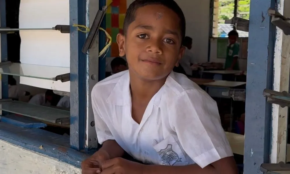 School student leaning out the window of Solevu Village school classroom on Malolo Island.