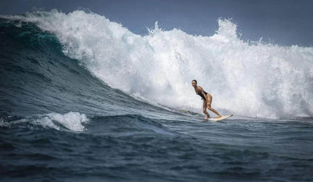 Woman surfing in Fiji at a break near Plantation Island Resort