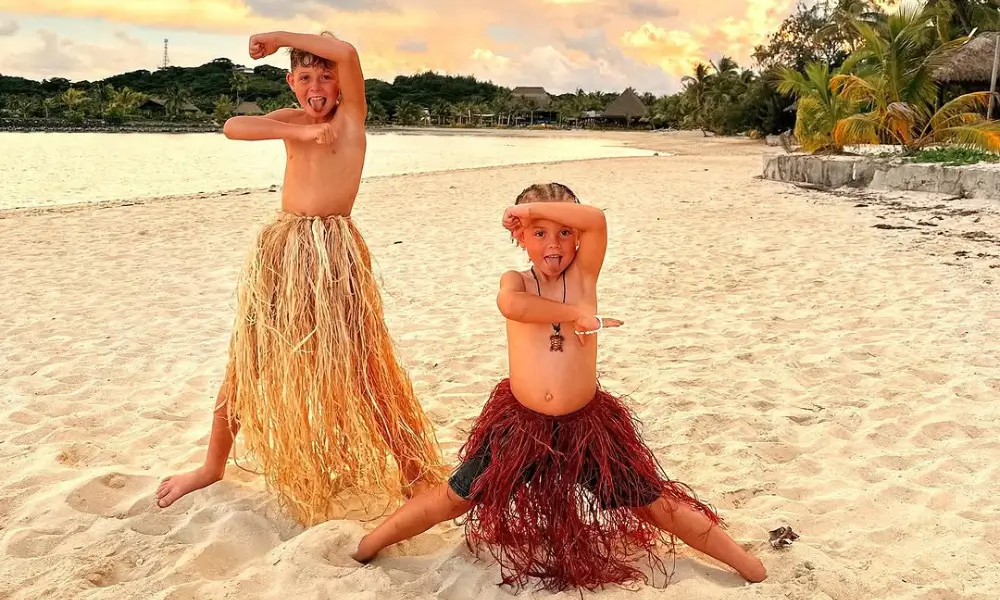 Two children stand on beach in traditional Fiji dress