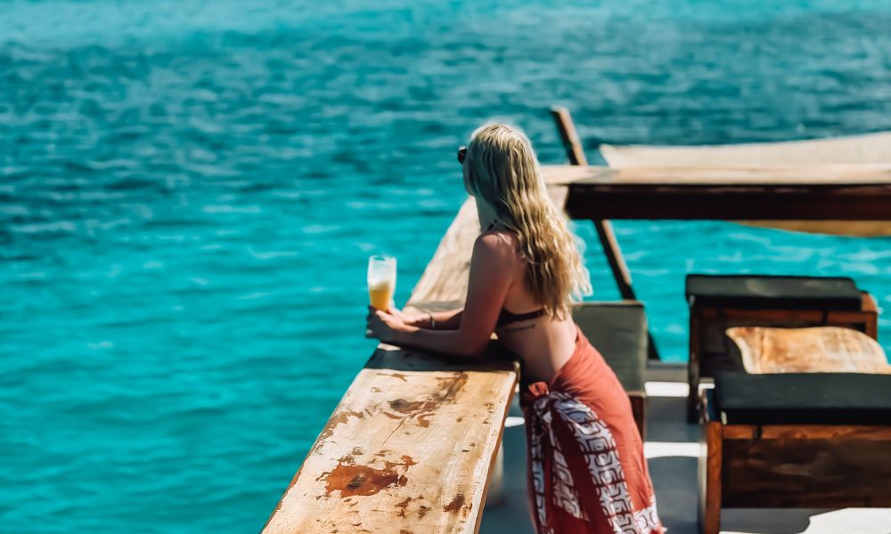 Woman with a drink looking at the ocean.