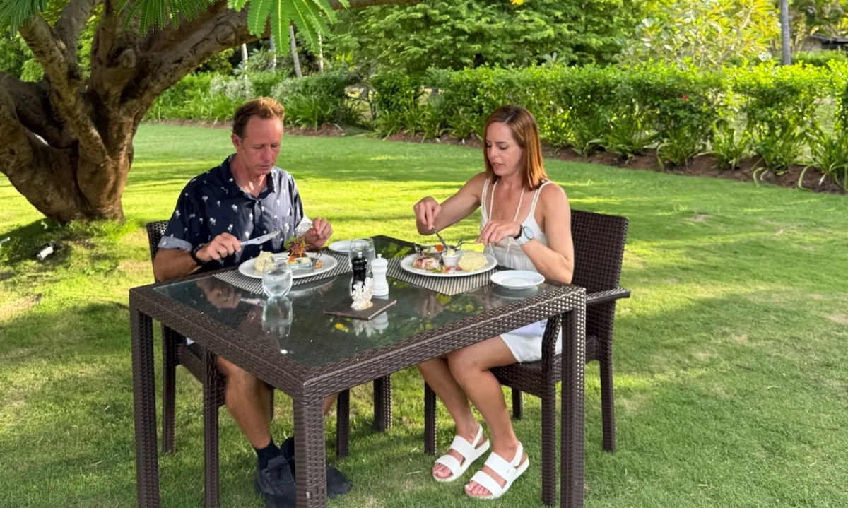Couple dining outdoors on a sunny lawn.