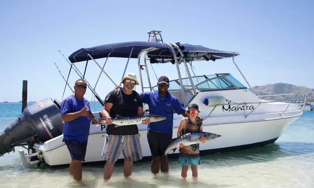 Guests and guides showing off their catch in front of their boat after their Fiji fishing trip