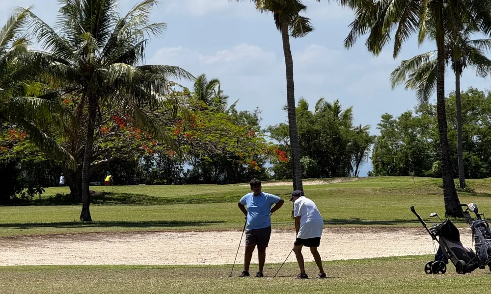 Golfers near a sand bunker on a tropical golf course