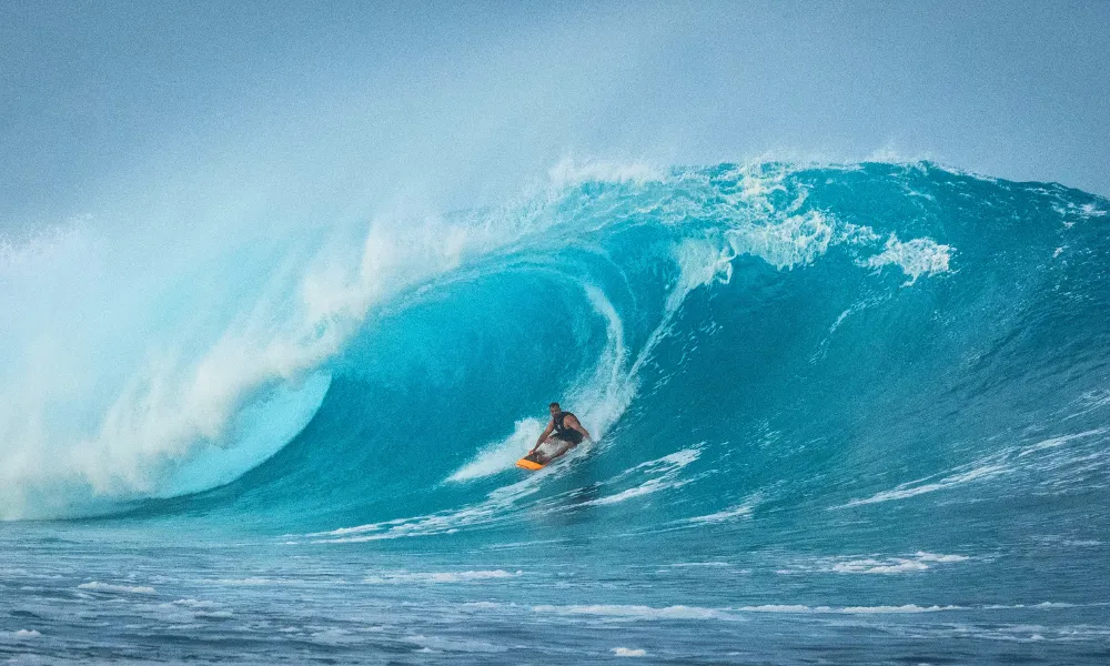 Surfer riding a large blue wave on an orange board