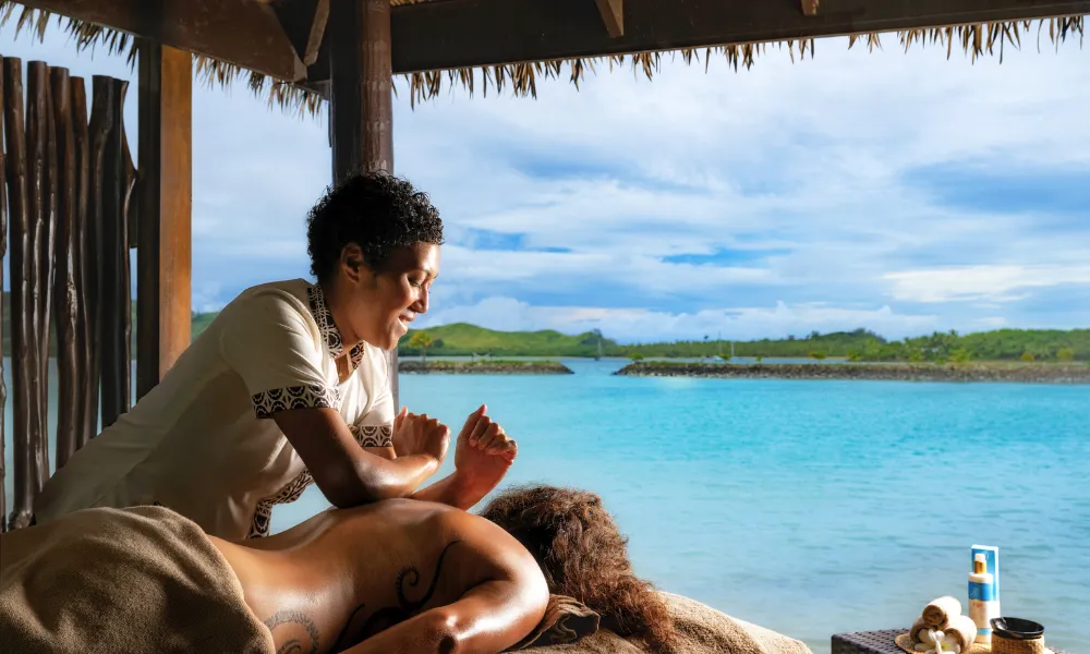 Woman receiving a massage at an outdoor spa overlooking the ocean