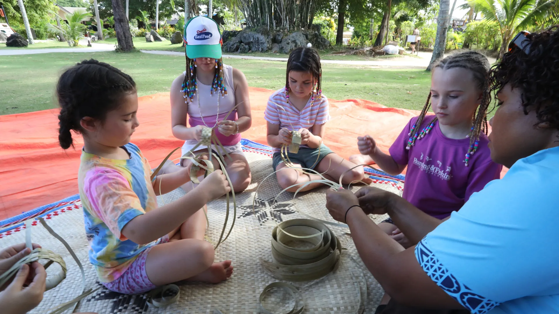 Children learning traditional Fijian basket weaving at the Coconut Kids Club