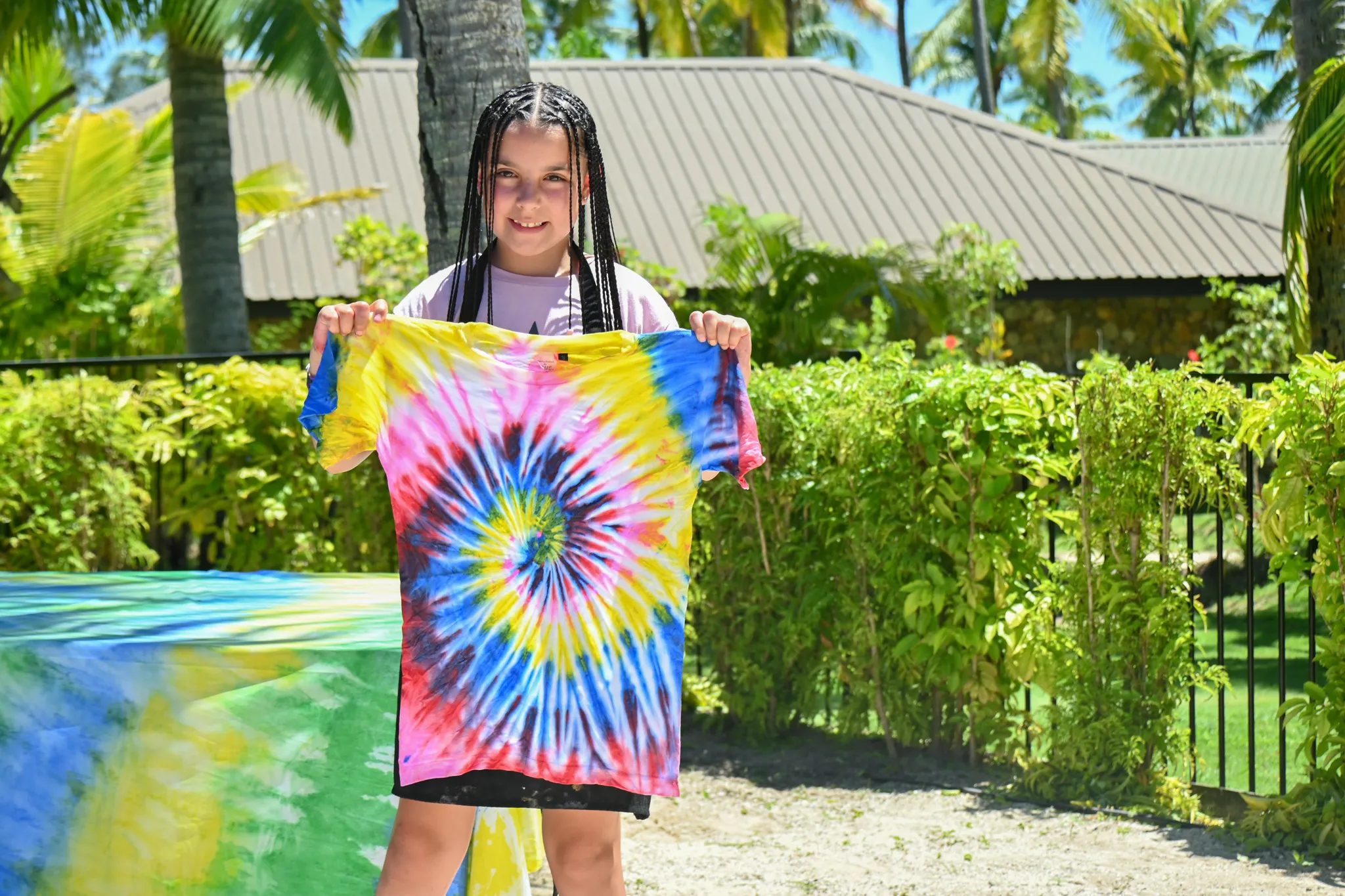Child holding up a freshly tie-dyed t-shirt at the Coconut Kids Club